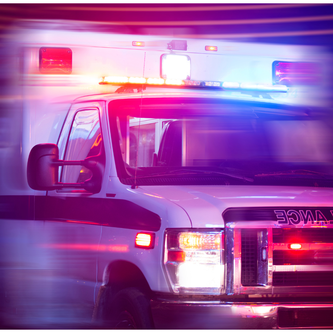 An ambulance with its lights on in motion